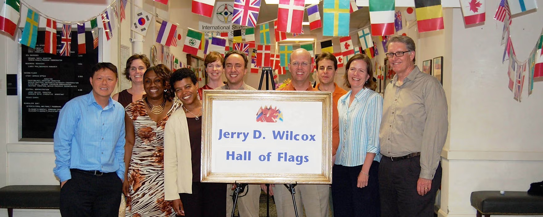 UT's International Office employees gather in hallway draped with world flags